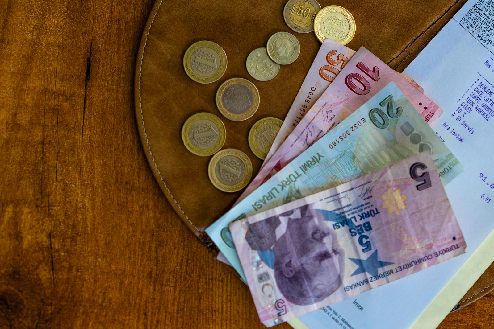 Close-up of Turkish lira coins and banknotes on a wooden surface alongside a receipt.