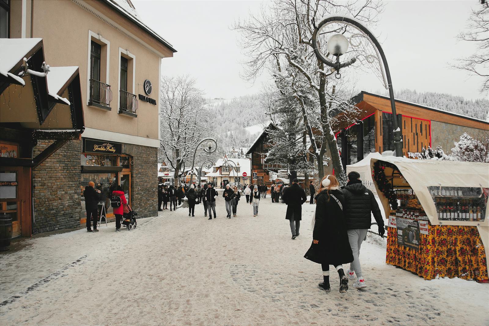 Snow-covered street in Zakopane, Poland, bustling with people.