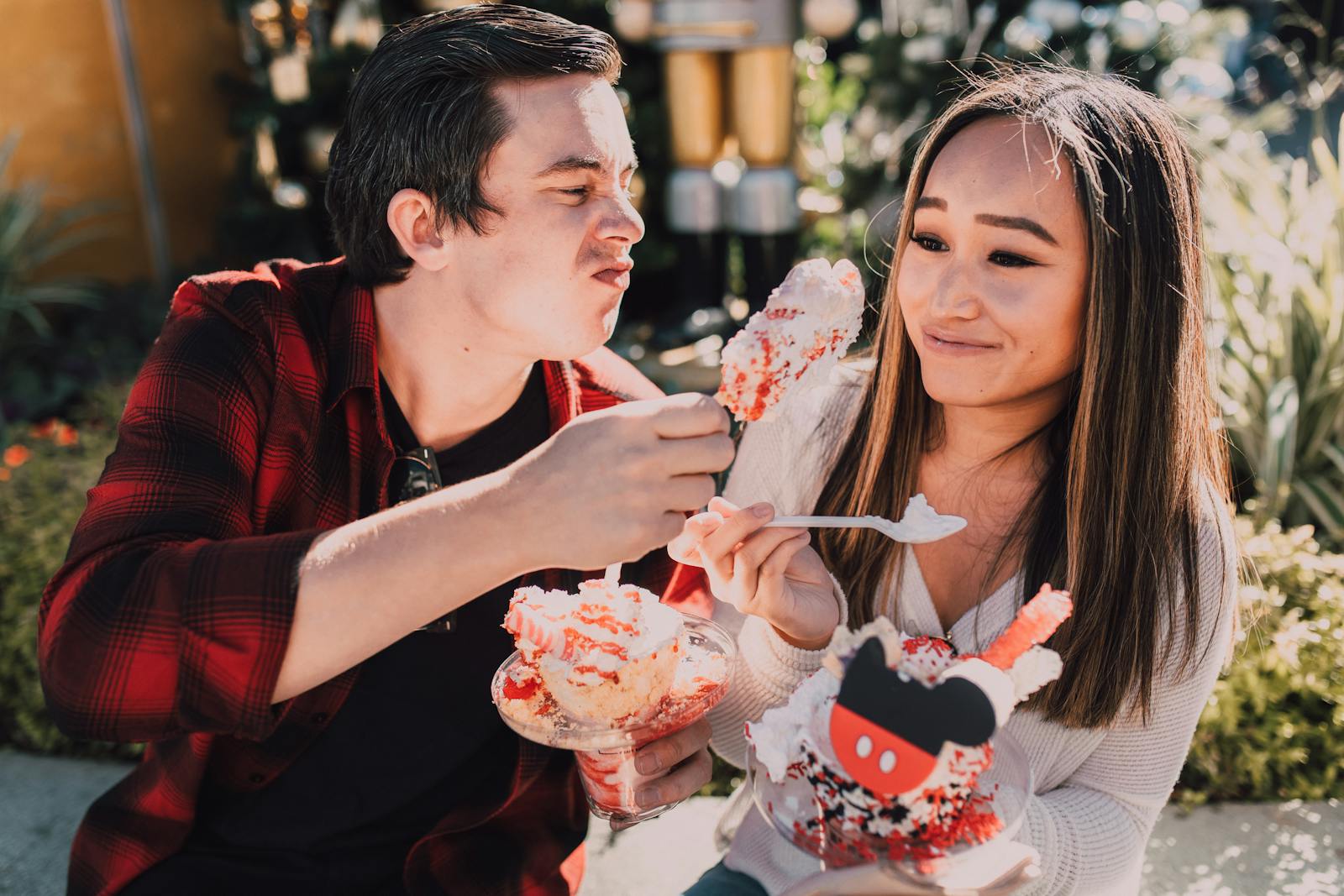 A young couple enjoying colorful desserts on a sunny day outdoors, sharing laughter.