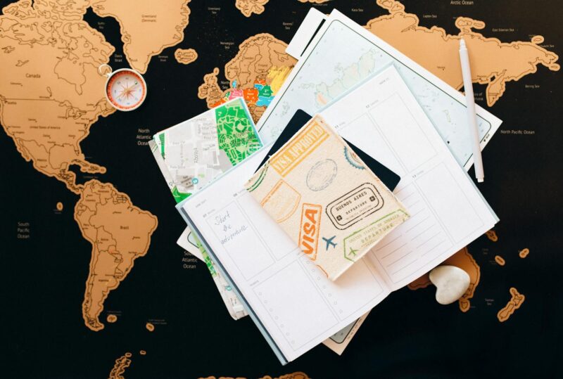 A flat lay of travel planning items on a map, featuring a compass, notebook, and guide for wanderlust enthusiasts.