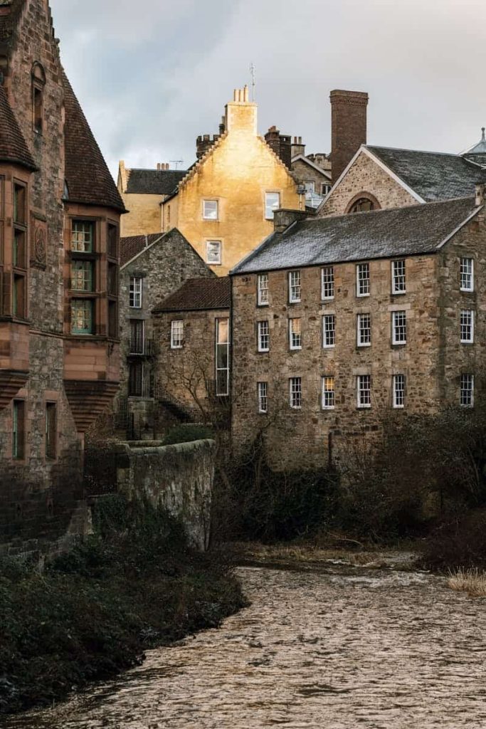 Charming view of historic stone buildings by a river in a quaint setting, showcasing architectural beauty.