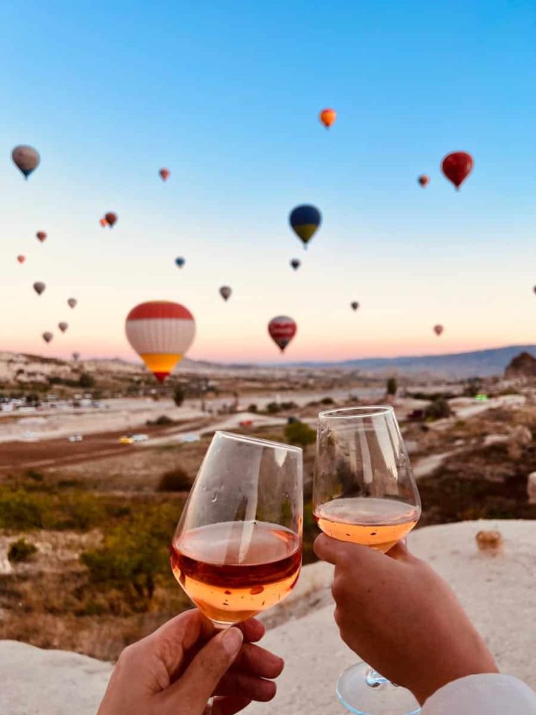 Cheers to adventure with a hot air balloon backdrop at a sunset picnic.