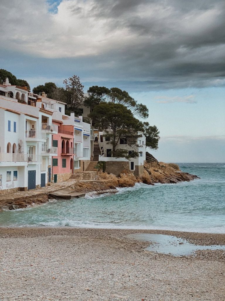 a row of houses next to the ocean under a cloudy sky