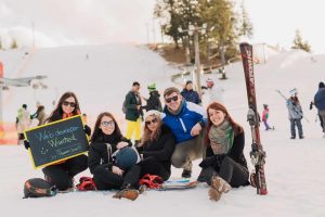 Best travel apps-group of people sitting on snow taking photo