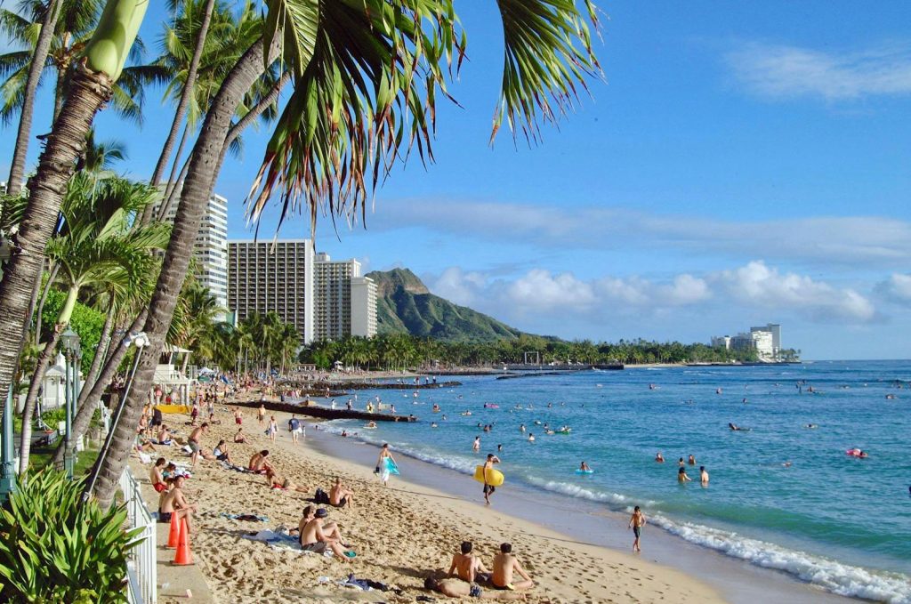 Vibrant scene of people enjoying Waikiki Beach under the tropical sun in Oahu, Hawaii. Travel to Hawaii.