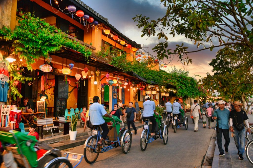 a group of people riding bikes down a street, things to do in Hoi An
