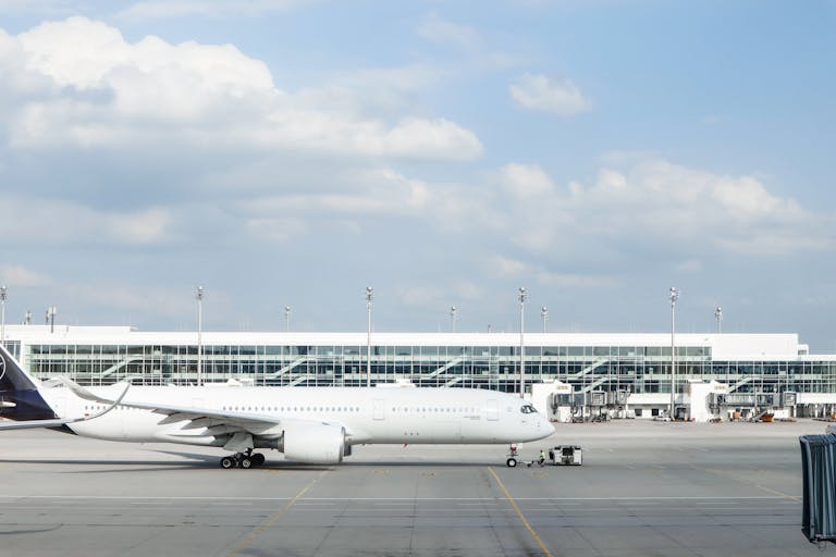 Widebody aircraft parked at an airport gate during clear day with terminal building visible.