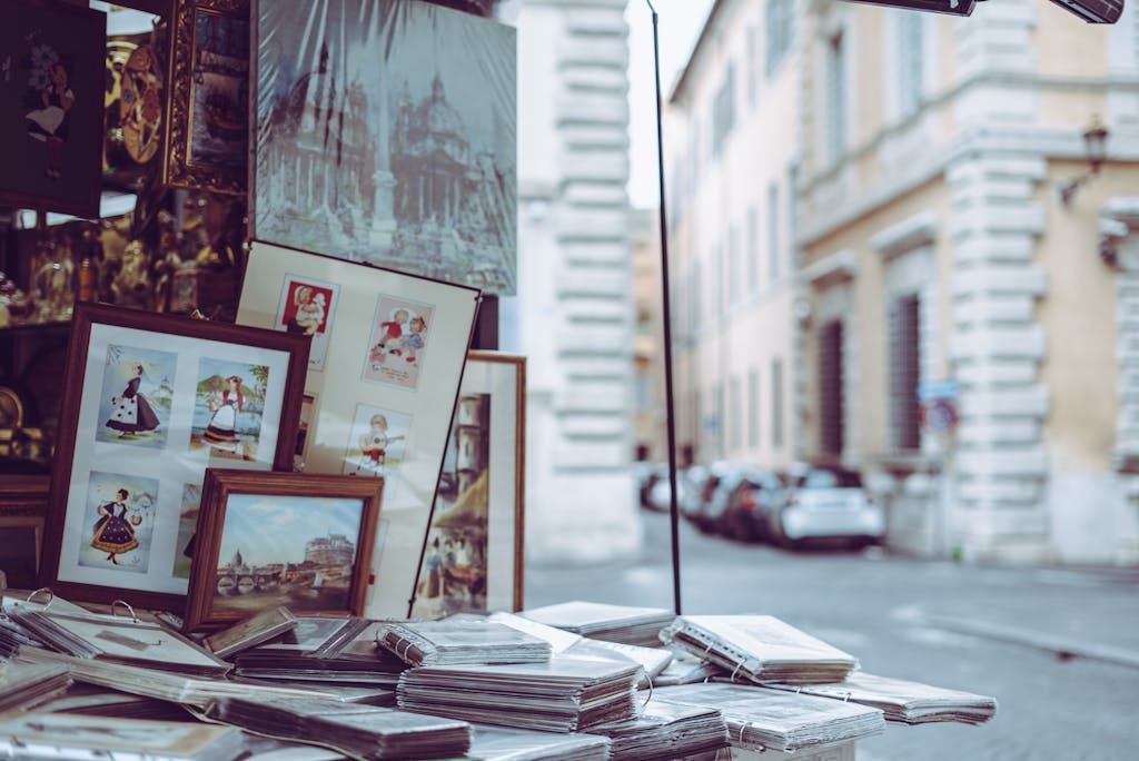 Framed art and pictures displayed at a street market in Monti neighborhood in Rome, capturing the city's vibrant outdoor shopping scene.